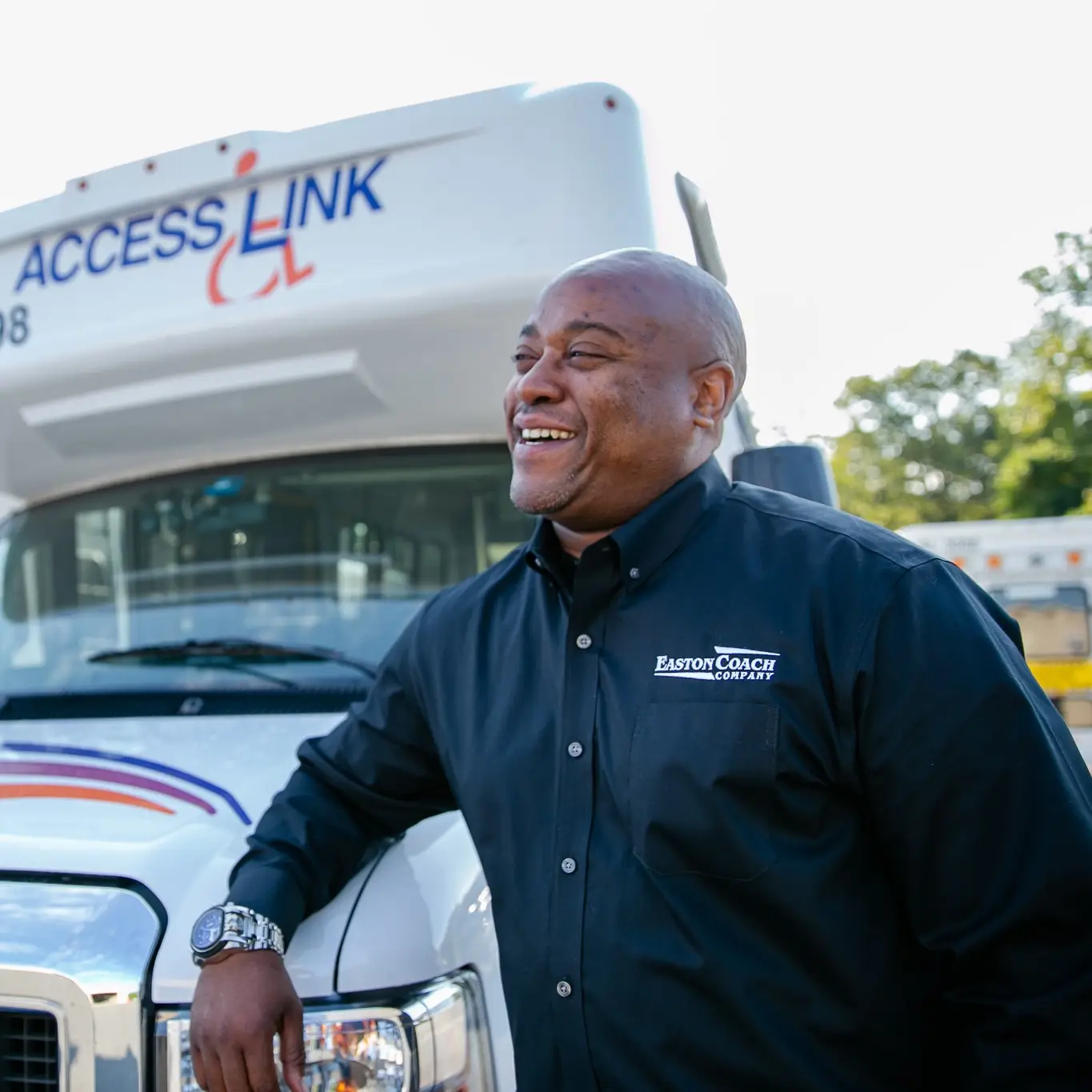 a smiling man in front of a bus